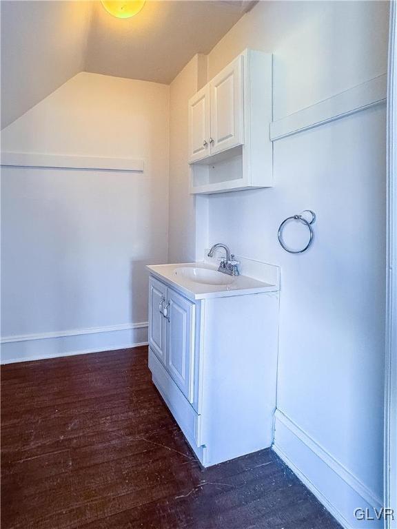 kitchen with dark hardwood / wood-style flooring, white cabinetry, lofted ceiling, and sink