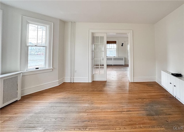 spare room featuring radiator heating unit and hardwood / wood-style flooring