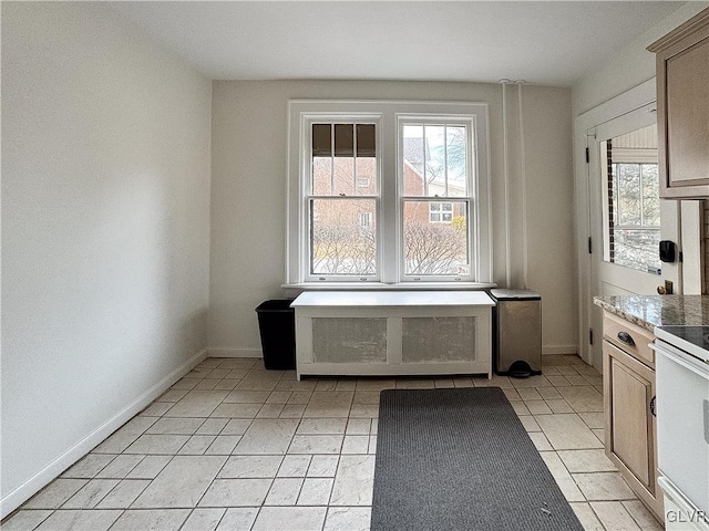 kitchen featuring white range with electric stovetop, light tile patterned floors, and a healthy amount of sunlight