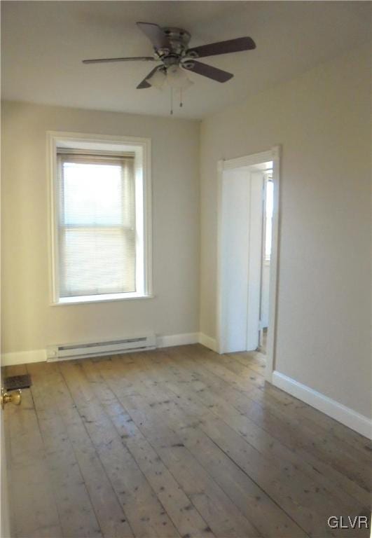 empty room featuring ceiling fan, baseboard heating, and light hardwood / wood-style flooring