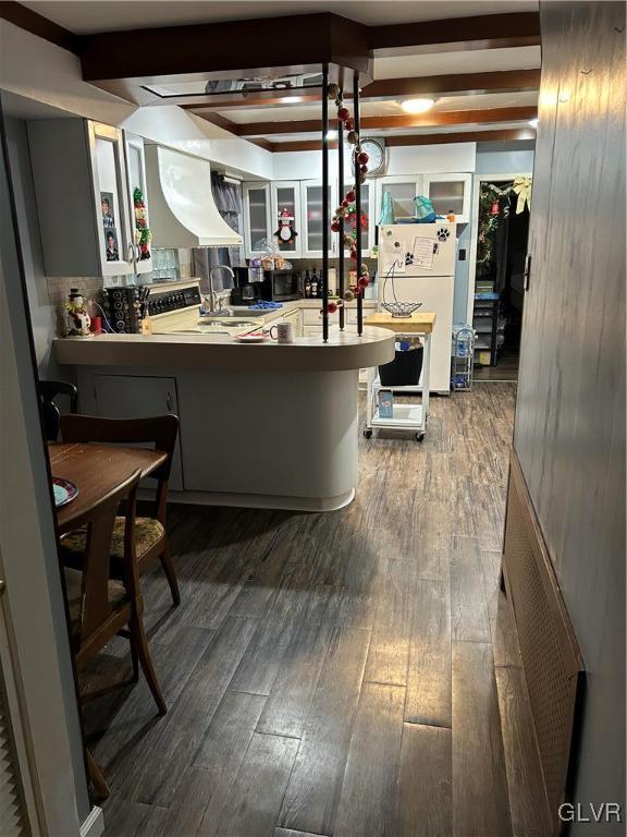 kitchen featuring a breakfast bar area, kitchen peninsula, white fridge, and wood-type flooring