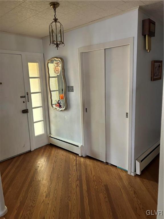 entryway with an inviting chandelier, a baseboard radiator, and wood-type flooring