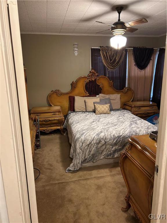 carpeted bedroom with ceiling fan and ornamental molding