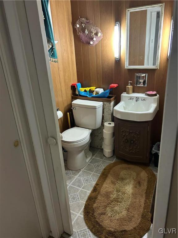 bathroom with tile patterned floors, wood walls, vanity, and toilet