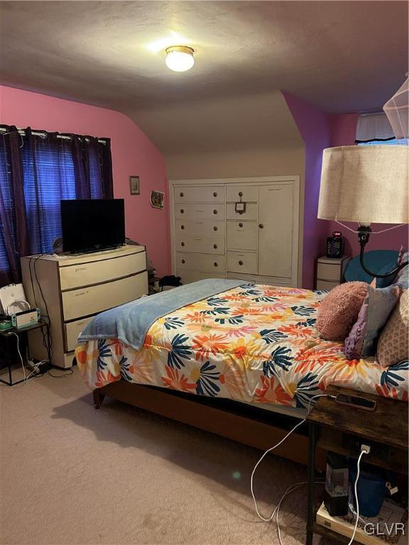 bedroom with light colored carpet and lofted ceiling