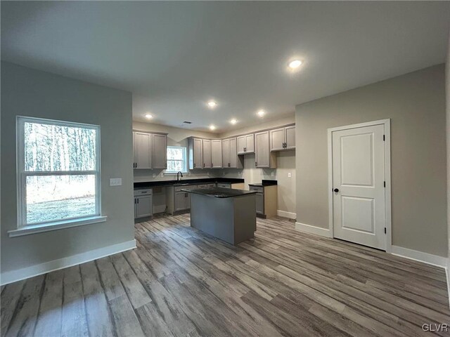 kitchen featuring dishwasher, sink, hardwood / wood-style floors, gray cabinets, and a kitchen island