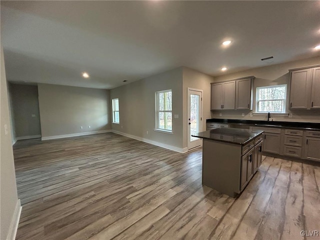 kitchen featuring gray cabinets, a kitchen island, a wealth of natural light, and light hardwood / wood-style flooring