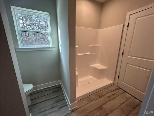 bathroom featuring a shower, hardwood / wood-style flooring, and toilet