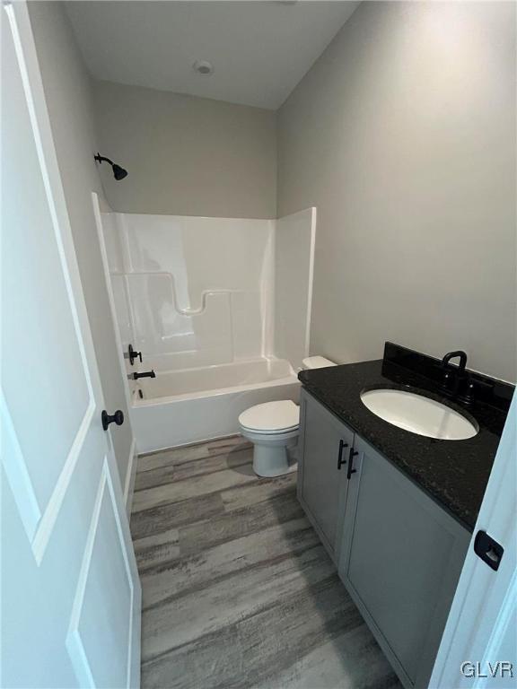 full bathroom featuring hardwood / wood-style flooring, vanity, bathtub / shower combination, and toilet