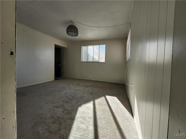 carpeted spare room with wooden walls