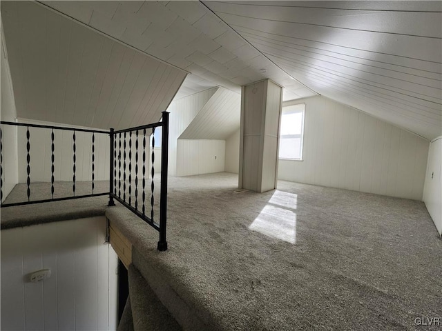 additional living space featuring wood walls, lofted ceiling, and light carpet