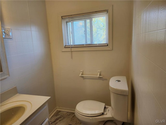 bathroom with vanity, toilet, and tile walls