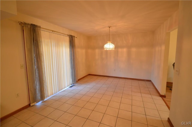 spare room featuring light tile patterned floors and a notable chandelier