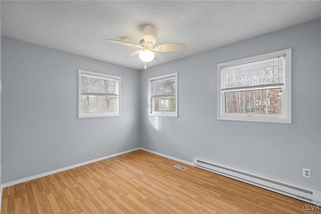 empty room featuring a textured ceiling, ceiling fan, light hardwood / wood-style floors, and baseboard heating