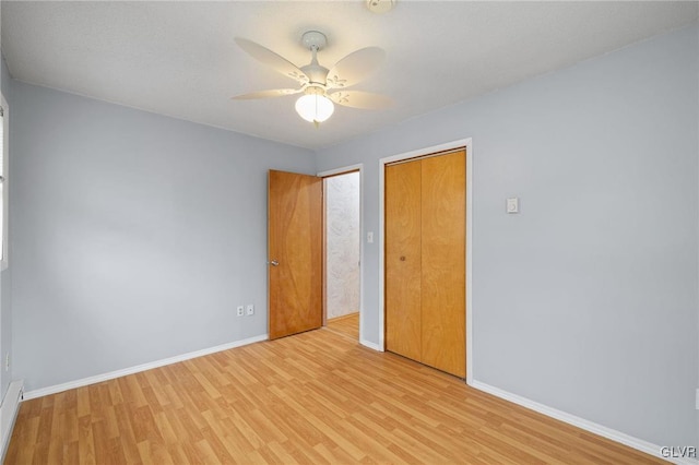 unfurnished bedroom featuring a closet, light hardwood / wood-style floors, ceiling fan, and a baseboard heating unit