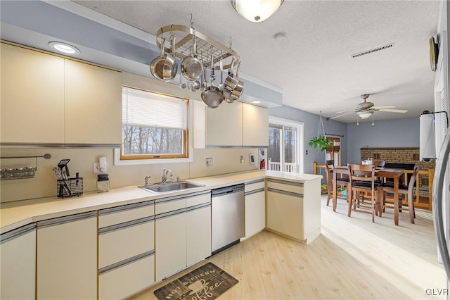 kitchen featuring dishwasher, sink, ceiling fan, light wood-type flooring, and a textured ceiling