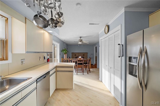 kitchen with kitchen peninsula, appliances with stainless steel finishes, light wood-type flooring, a textured ceiling, and ceiling fan