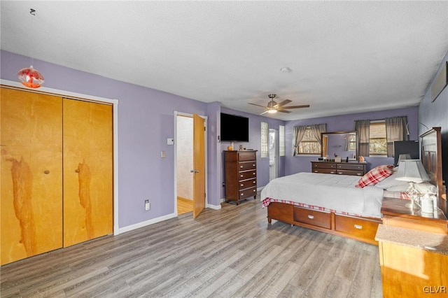 bedroom with a textured ceiling, a closet, light hardwood / wood-style floors, and ceiling fan