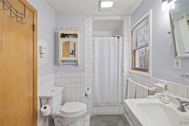 bathroom with a textured ceiling, toilet, tile walls, and tile patterned floors