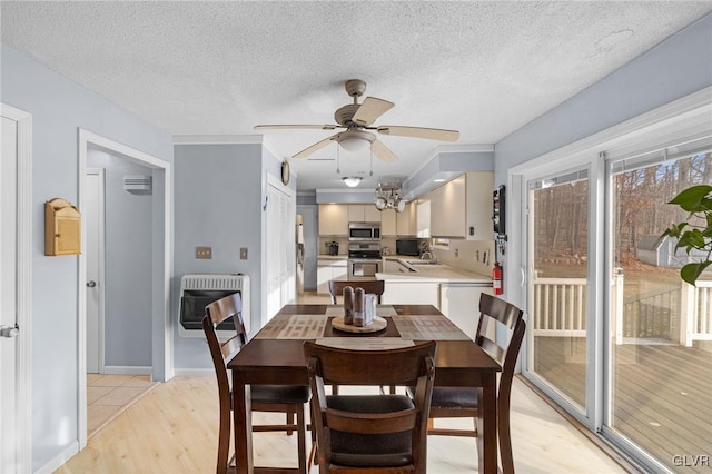 dining room with ceiling fan, sink, heating unit, a textured ceiling, and light wood-type flooring