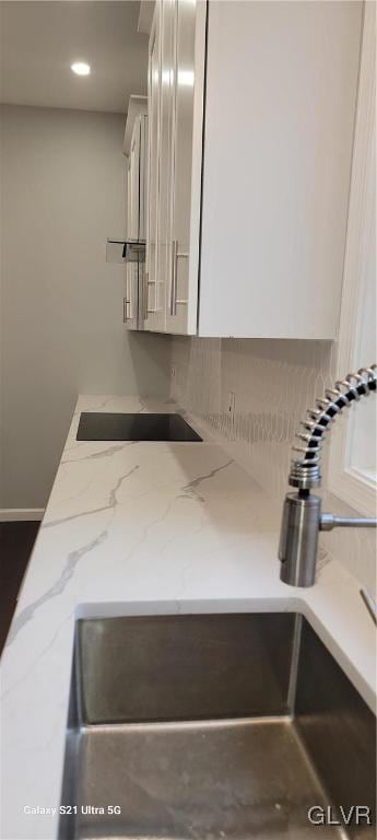 interior details with white cabinetry and light stone countertops