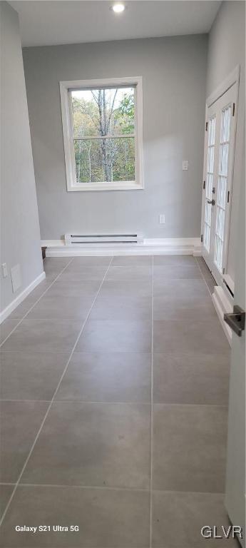 interior space with tile patterned floors, a baseboard heating unit, and french doors