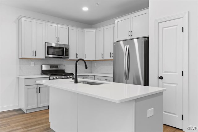 kitchen with white cabinets, appliances with stainless steel finishes, sink, and an island with sink