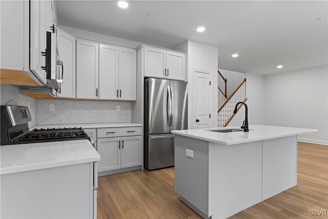 kitchen with sink, white cabinetry, stainless steel appliances, and a kitchen island with sink