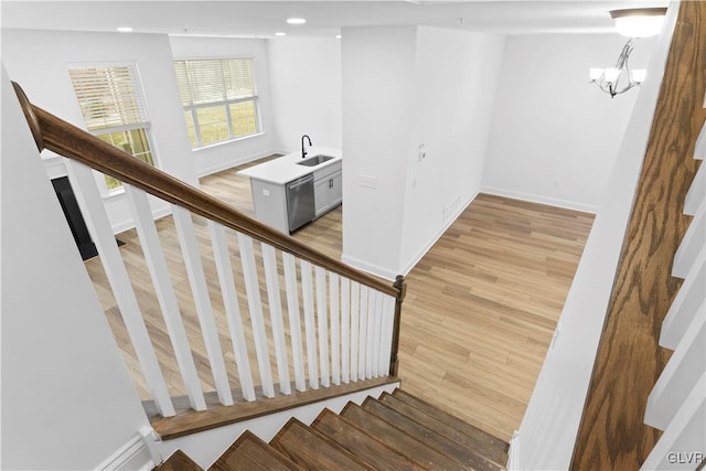 stairs with wood-type flooring, sink, and a chandelier