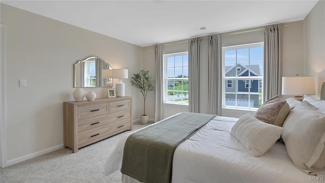 bedroom featuring light carpet and multiple windows