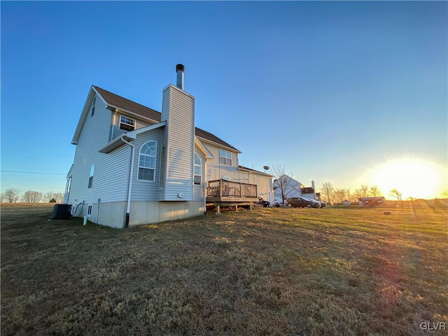 back of house with a deck, cooling unit, a chimney, and a yard