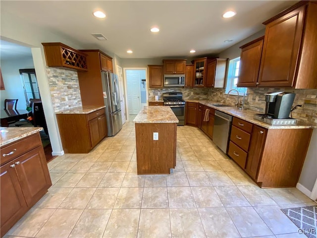 kitchen with a sink, brown cabinets, appliances with stainless steel finishes, and a center island