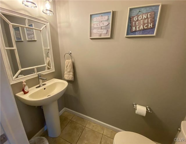 half bathroom featuring tile patterned floors, toilet, and baseboards