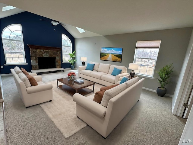 carpeted living room featuring a fireplace, lofted ceiling with skylight, a healthy amount of sunlight, and baseboards