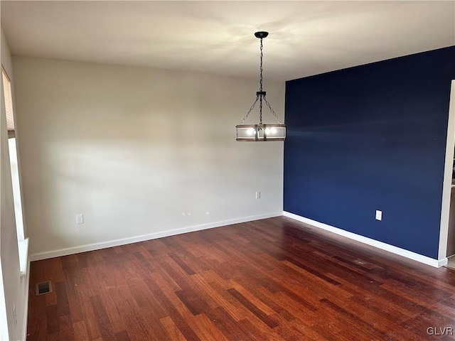 spare room featuring visible vents, baseboards, and dark wood-style flooring