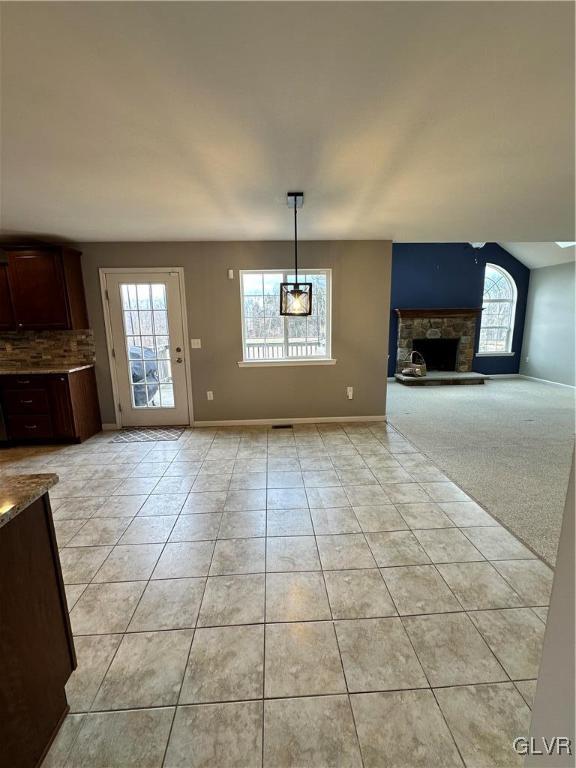 unfurnished living room featuring light tile patterned floors, a fireplace, and baseboards