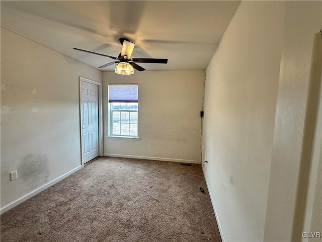 empty room featuring carpet flooring, baseboards, and a ceiling fan