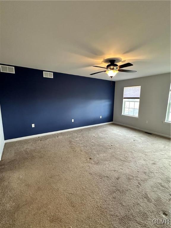 unfurnished room featuring visible vents, baseboards, a ceiling fan, and carpet flooring