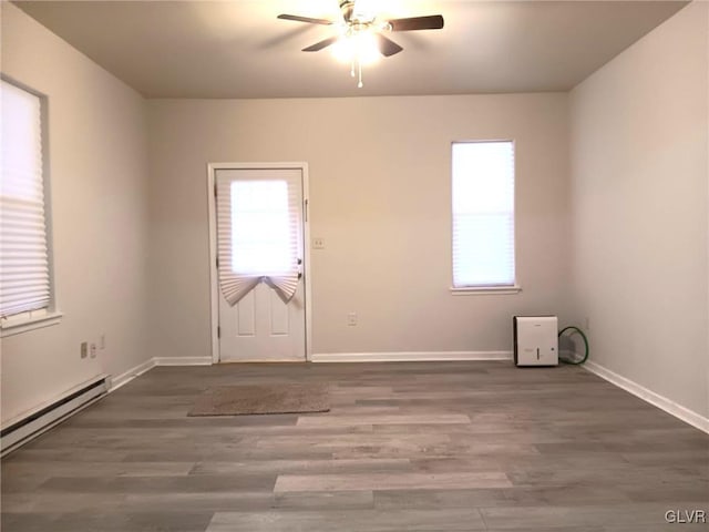 empty room with baseboard heating, ceiling fan, and dark hardwood / wood-style flooring