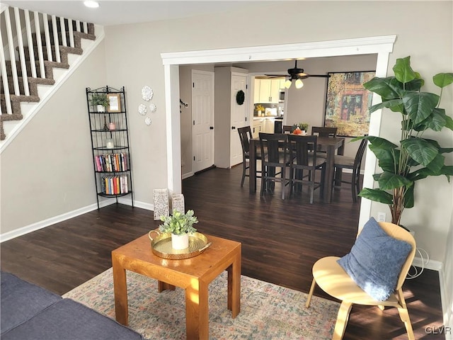 living room featuring ceiling fan and dark wood-type flooring