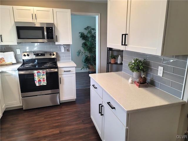 kitchen with decorative backsplash, white cabinetry, dark wood-type flooring, and appliances with stainless steel finishes