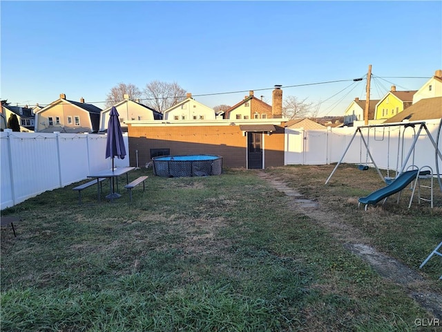 view of yard with a fenced in pool and a playground