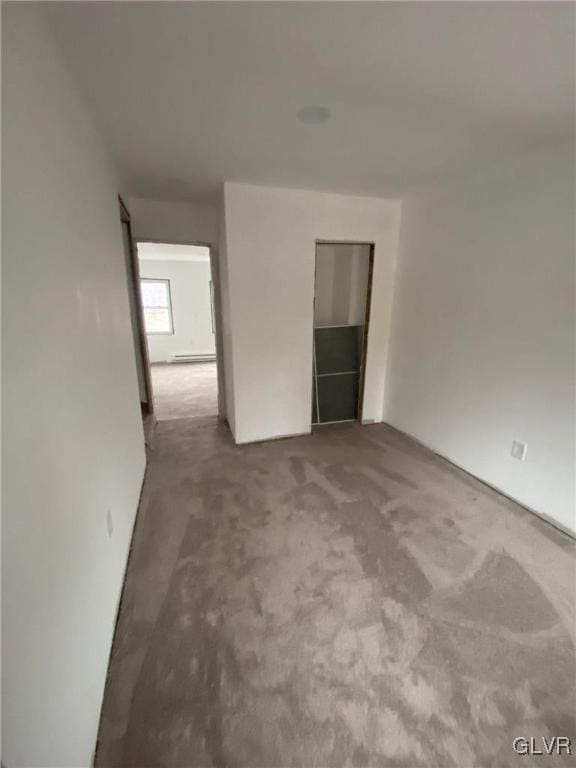 unfurnished room featuring carpet and a baseboard radiator