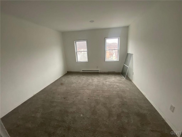 carpeted empty room featuring a baseboard heating unit