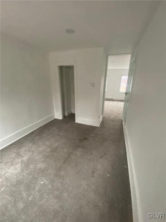 carpeted empty room featuring baseboard heating