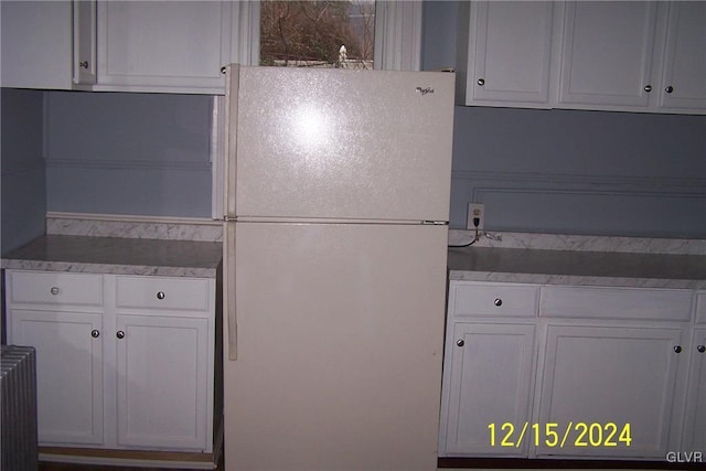 kitchen with white refrigerator, white cabinetry, and radiator heating unit