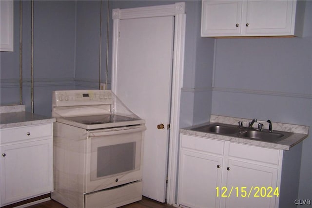 kitchen featuring white range with electric cooktop, sink, and white cabinets