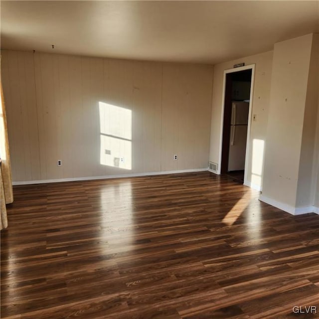 empty room with dark hardwood / wood-style flooring and wooden walls