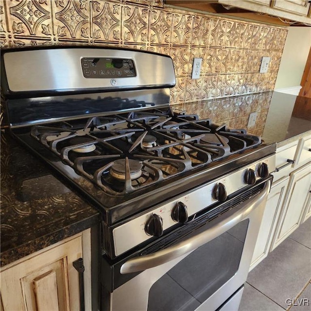 room details featuring decorative backsplash, dark stone countertops, and gas range