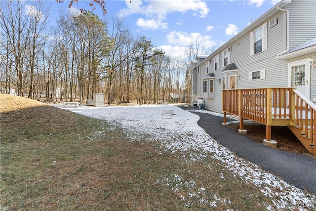 yard layered in snow featuring a wooden deck and central AC unit